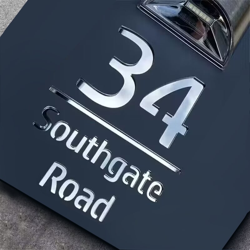 Square solar house plaque lit up at night beside a front door